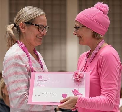 Woman receiving pink certificate during breast cancer awareness event