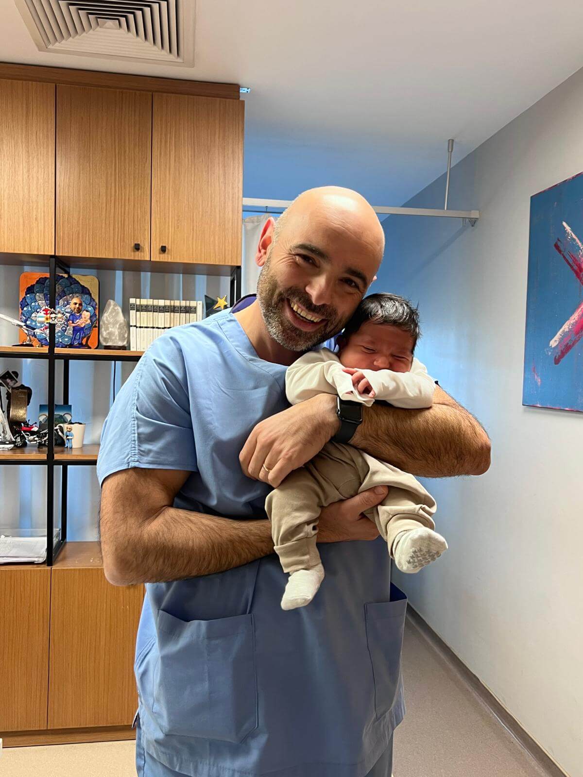 Smiling doctor holding newborn baby in clinic, gentle pediatric care moment
