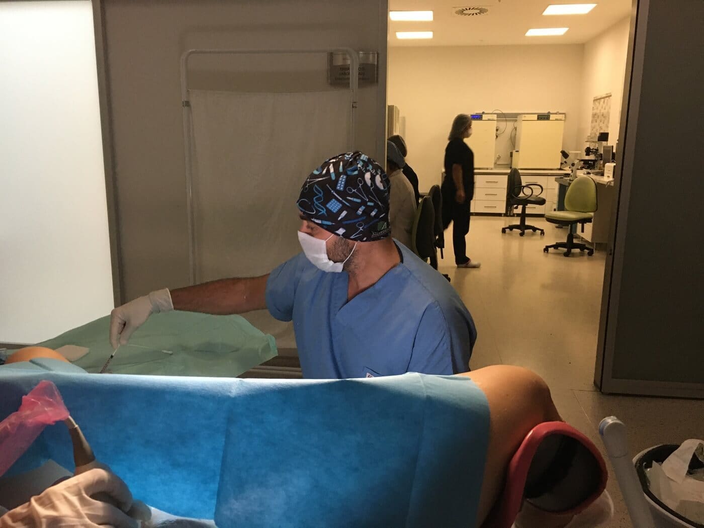 Doctor performing gynecological examination in clinical setting with patient and medical equipment