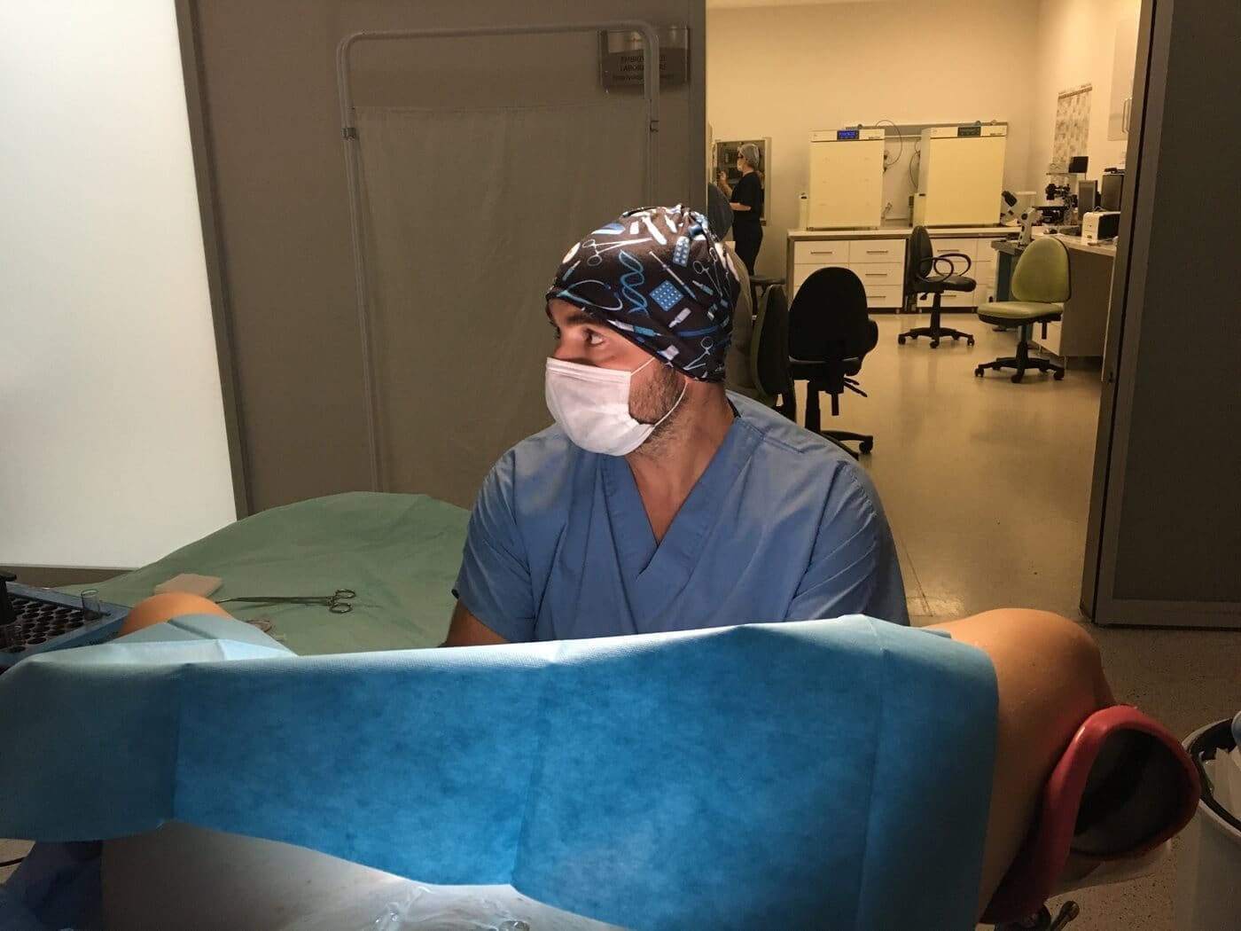 Doctor in scrubs and mask assisting during a medical procedure