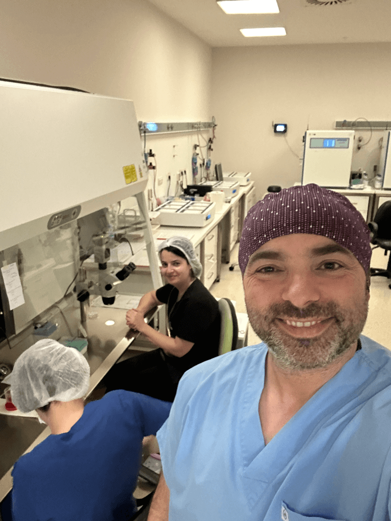 Laboratory team working in sterile environment with scientists using laminar flow hood and medical equipment, researcher taking selfie in cleanroom lab with colleagues performing scientific procedures