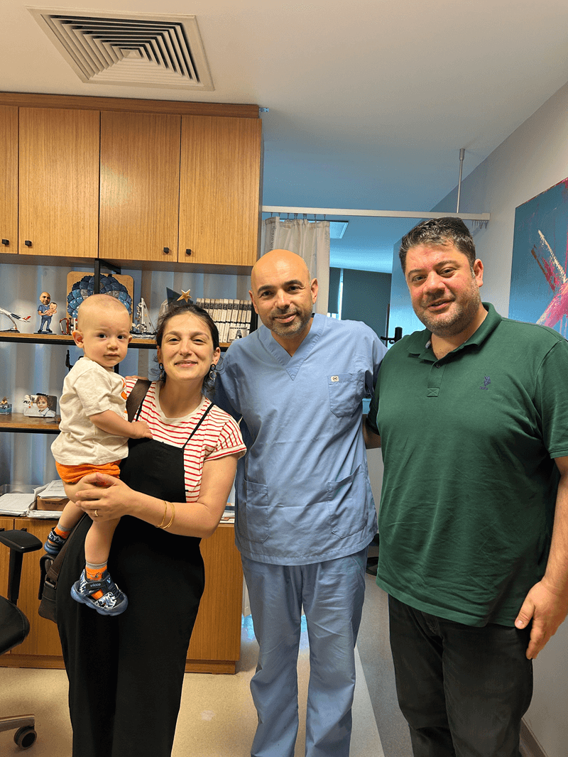 Family with doctor holding toddler in clinic room after medical visit