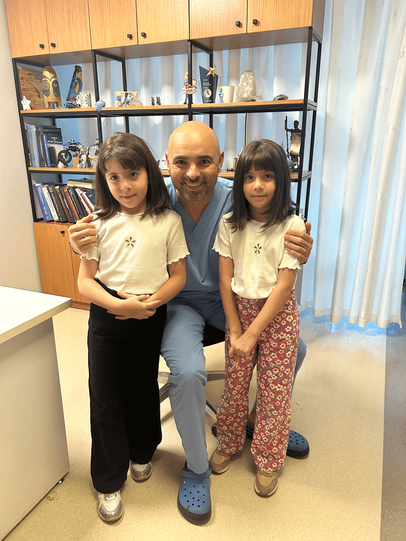 Smiling doctor sitting with two young girls in a clinic office