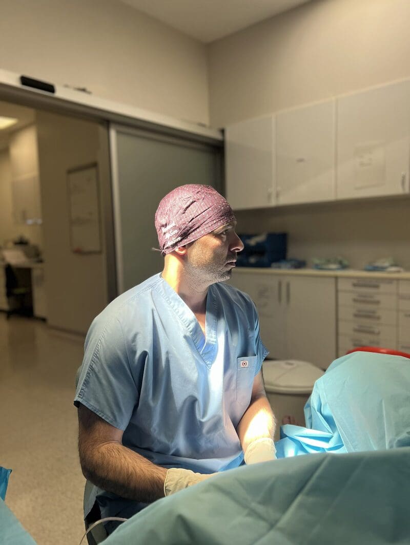 Surgeon in scrubs performing a procedure in a clinical operating room